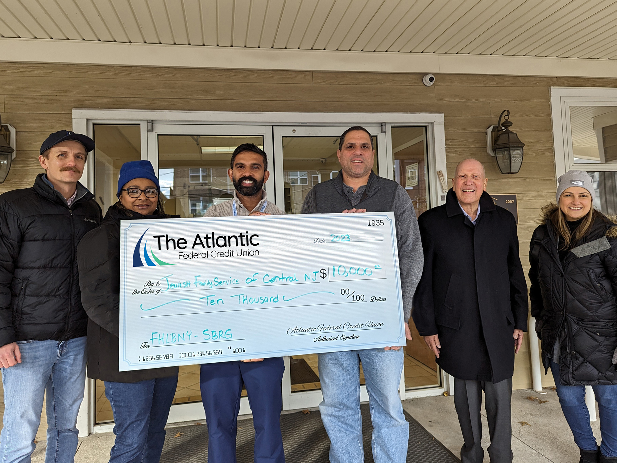 Photo of representatives from Jewish Family Service of Central NJ accepting an oversized check of $10,000 through the FHLBNY SBRG from representatives of The Atlantic