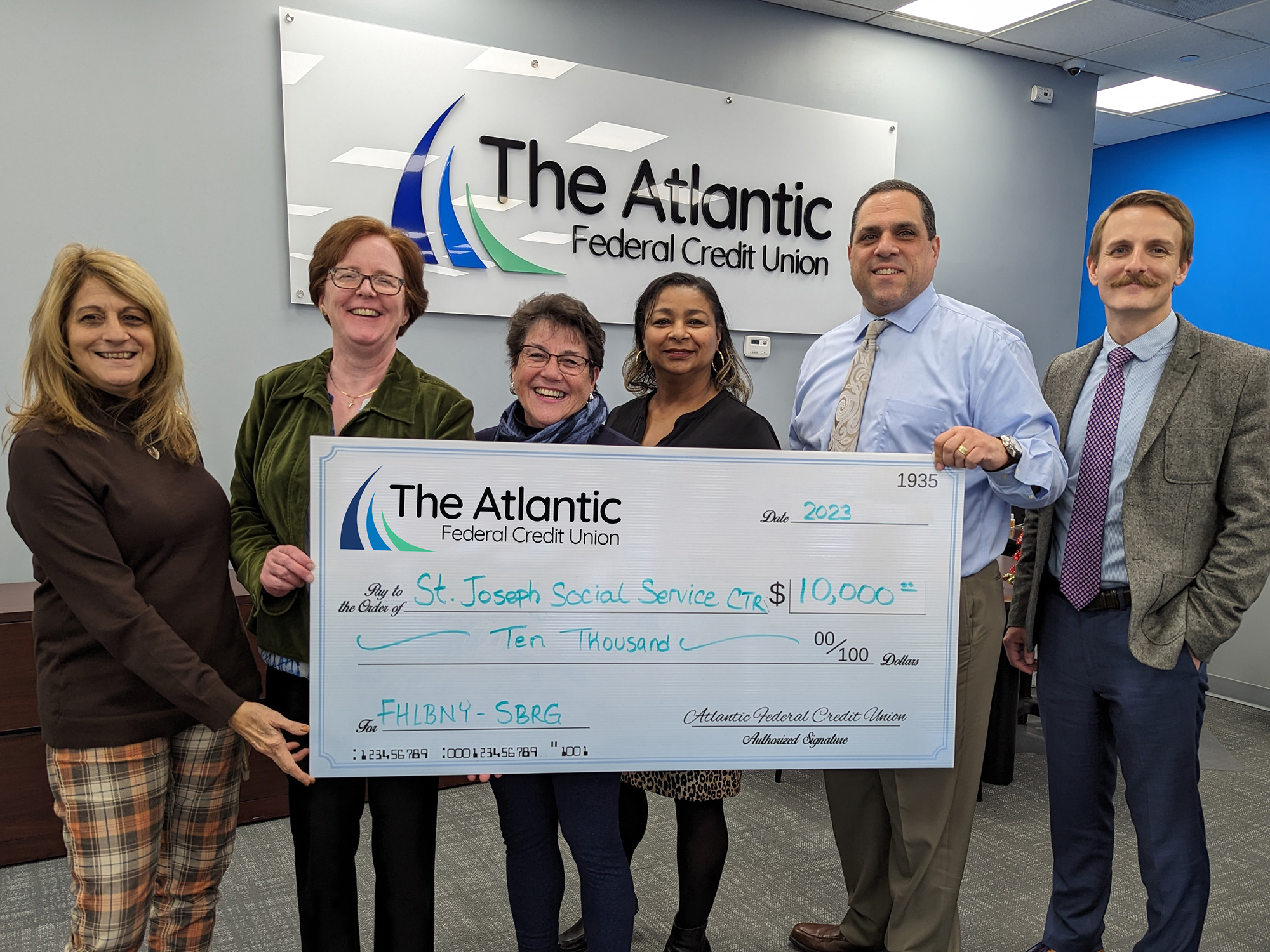 Photo of representatives from St. Joseph Social Service Center accepting an oversized check of $10,000 through the FHLBNY SBRG from representatives of The Atlantic